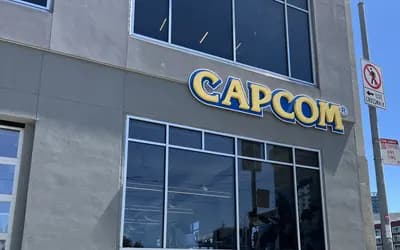 Capcom building facade with the yellow-and-blue Capcom logo above glass windows, with traffic signs beside it