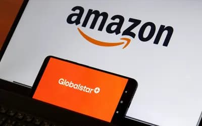 Smartphone displaying the Globalstar logo in front of a laptop screen showing the Amazon logo