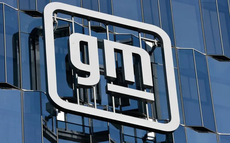 White General Motors (GM) logo on the side of a building with a blue glass facade
