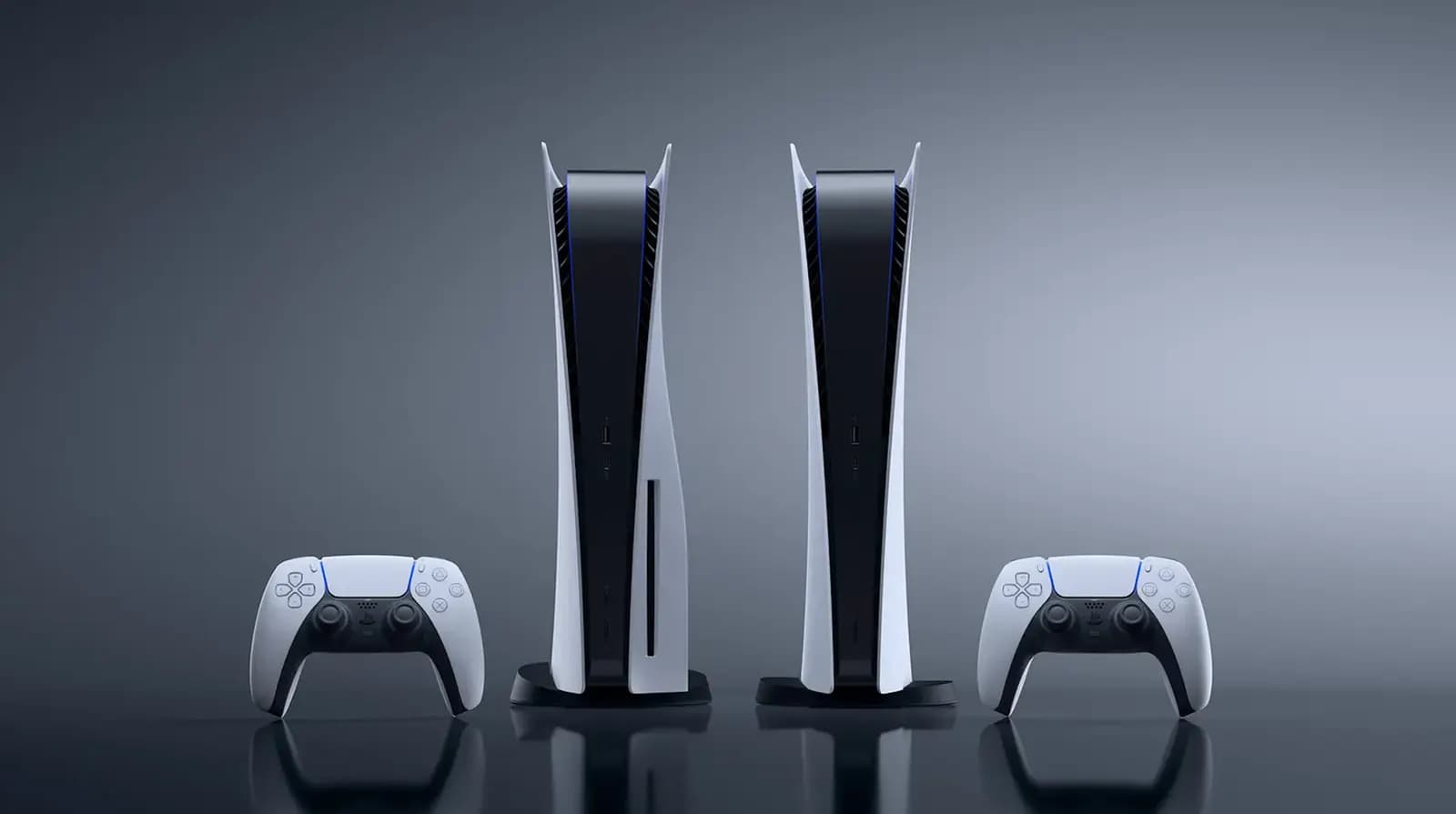 Two PlayStation 5 consoles stand side by side with two white DualSense controllers against a gray background.