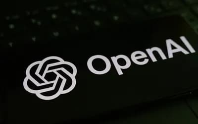 Klavyenin üzerinde duran, ekranında OpenAI logosu ve yazısı görünen siyah telefon