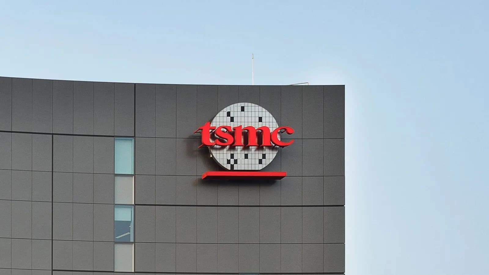 TSMC logo and wafer graphic on a gray-facade building under a clear light blue sky