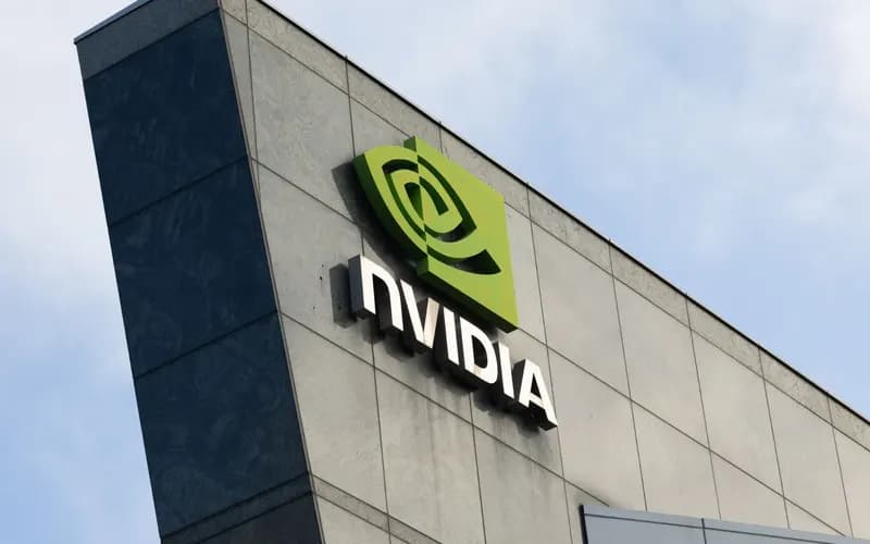 Mavi gökyüzü altında, gri ve koyu cepheli bir binanın üzerinde yer alan yeşil Nvidia logosu ve yazısı