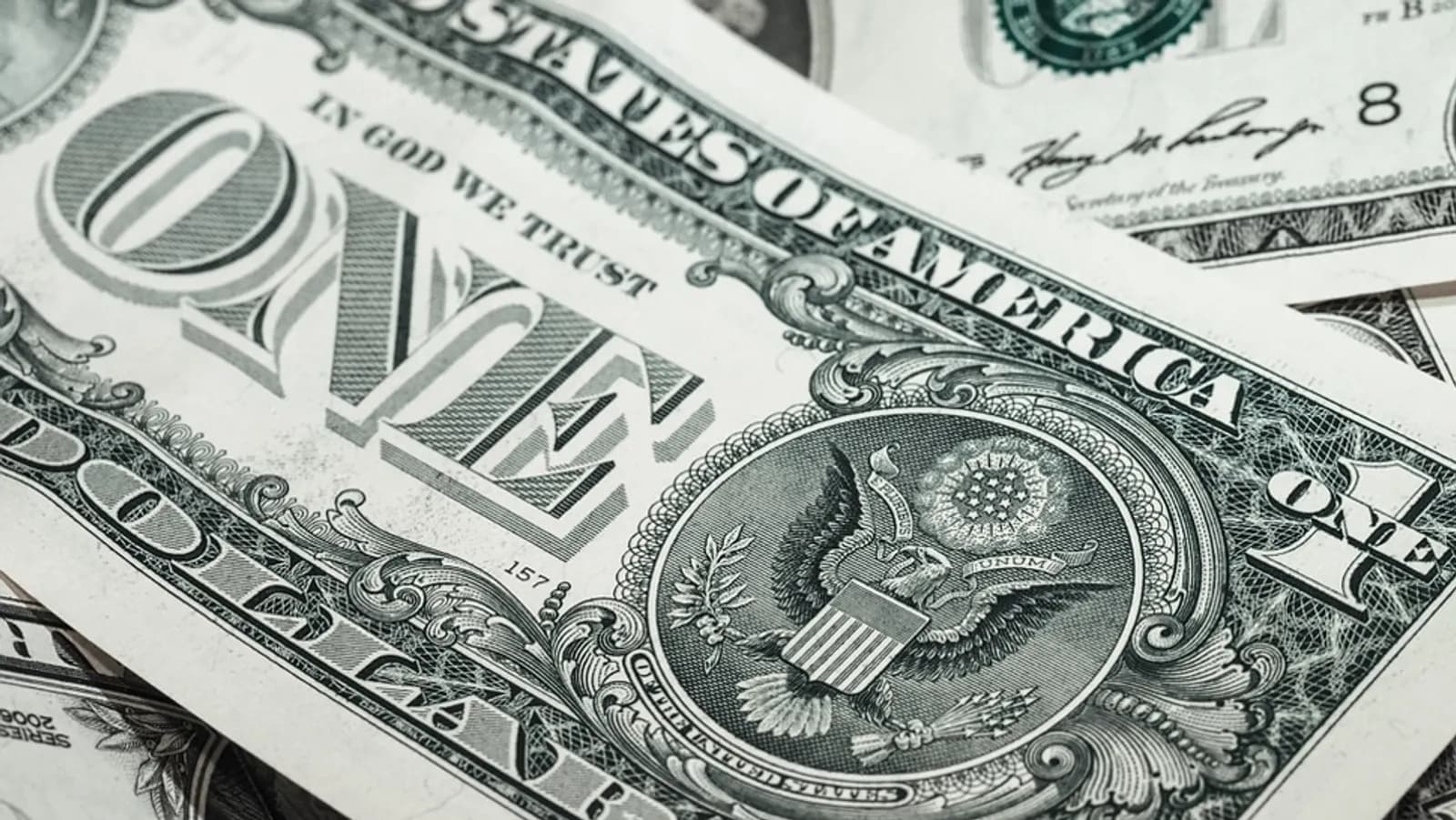 Yakın çekimde ABD bir dolarlık banknotlar; 'ONE' yazısı, Büyük Mühür ve kartal deseni görünüyor