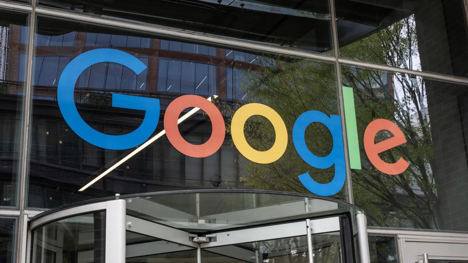 Google logo on an office building's glass facade, above a revolving door entrance