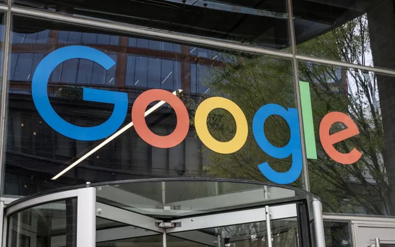 Google logo on an office building's glass facade, above a revolving door entrance