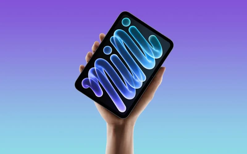 Hand holding a tablet with a colorful "mini" wallpaper on its screen, against a purple-blue gradient background