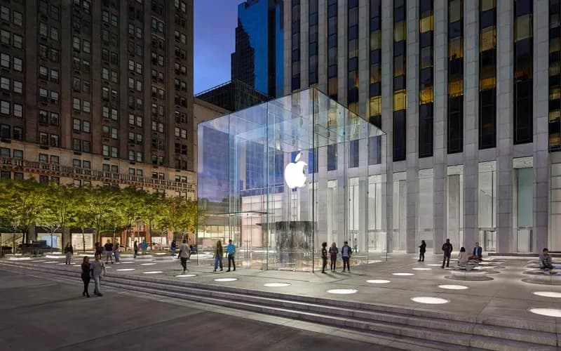 Alacakaranlıkta Manhattan'daki Apple Fifth Avenue mağazasının cam küpü, çevresindeki meydan, basamaklar ve yürüyen insanlar
