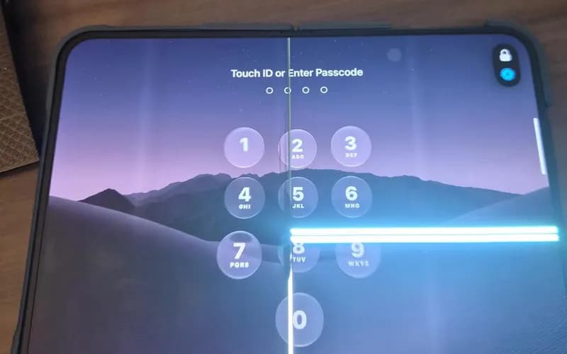 Katlanabilir bir tabletin kilit ekranında şifre girişi görünüyor; ekranda dikey çizgi ve parlak yatay çizgi arızaları var.