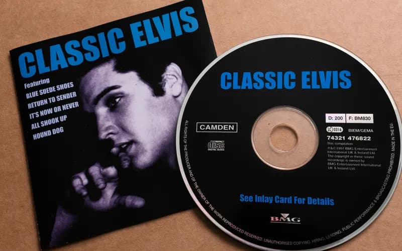 Kahverengi zemin üzerinde 'Classic Elvis' yazılı CD kapağı ve yanında BMG etiketli siyah-mavi compact disk.