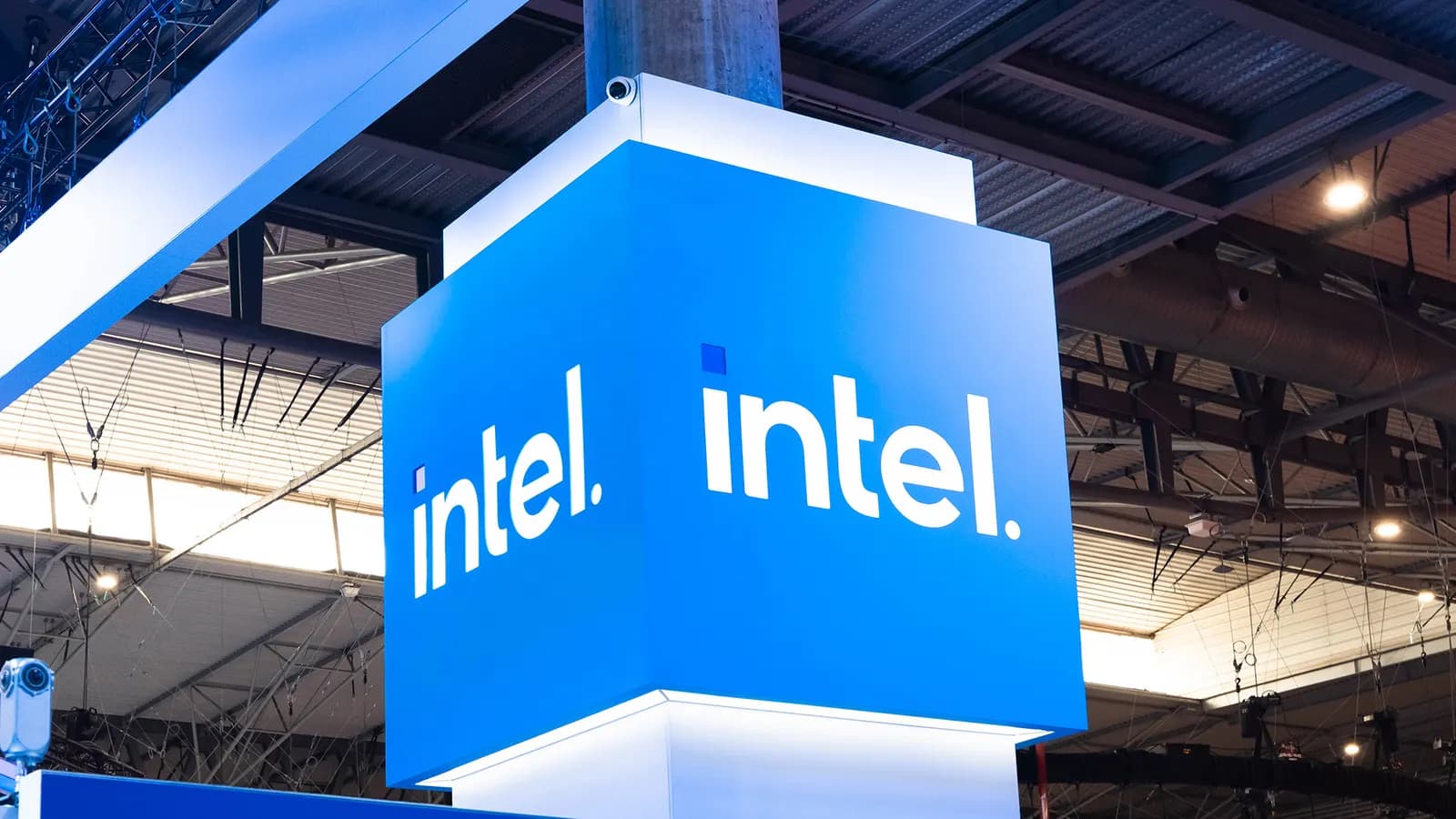 Fuar salonunda tavandan sarkan, mavi zemin üzerinde beyaz Intel logosu taşıyan küp biçimli aydınlatmalı tabela