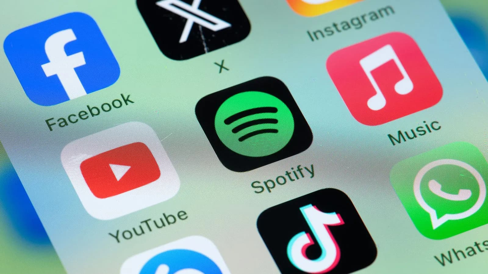 Telefon ekranında Facebook, X, Instagram, Spotify, Apple Music, YouTube, TikTok ve WhatsApp uygulama simgeleri yakından görünüyor