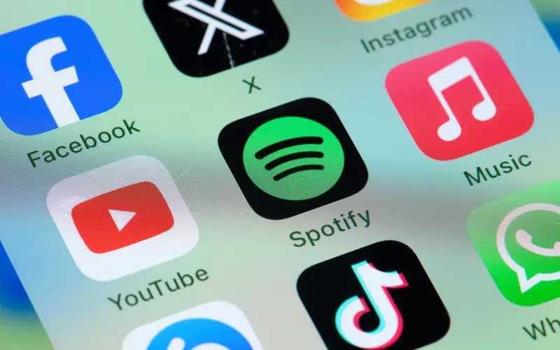 Close-up of a phone screen showing Facebook, X, Instagram, Spotify, Apple Music, YouTube, TikTok and WhatsApp app icons