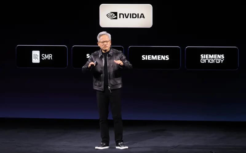 Speaker in a black leather jacket on stage, with NVIDIA, Rolls-Royce SMR, Siemens and Siemens Energy logos on the screen behind.
