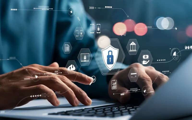 Hands typing on a laptop, with lock, shield, bank, and cloud icons overlaid to represent cybersecurity