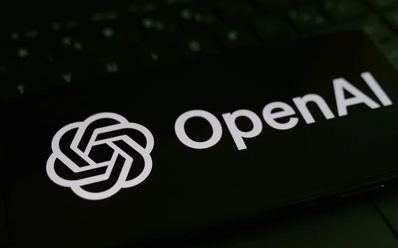 Klavyenin üzerinde duran, ekranında OpenAI logosu ve yazısı görünen siyah telefon