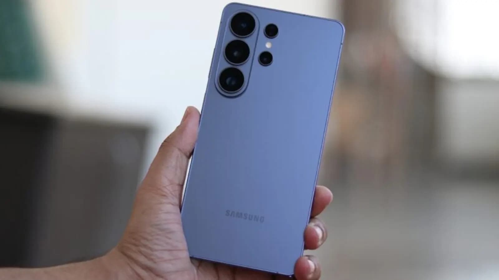 Elde tutulan mor renkli Samsung akıllı telefonun arka yüzü ve üç kameralı modül