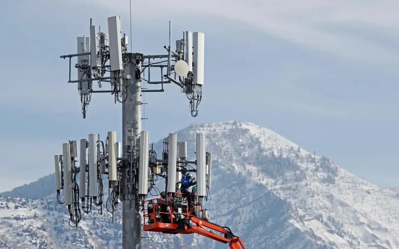 Karlı dağların önünde, hücresel kulenin antenlerinde vinç sepetiyle çalışan teknisyenler