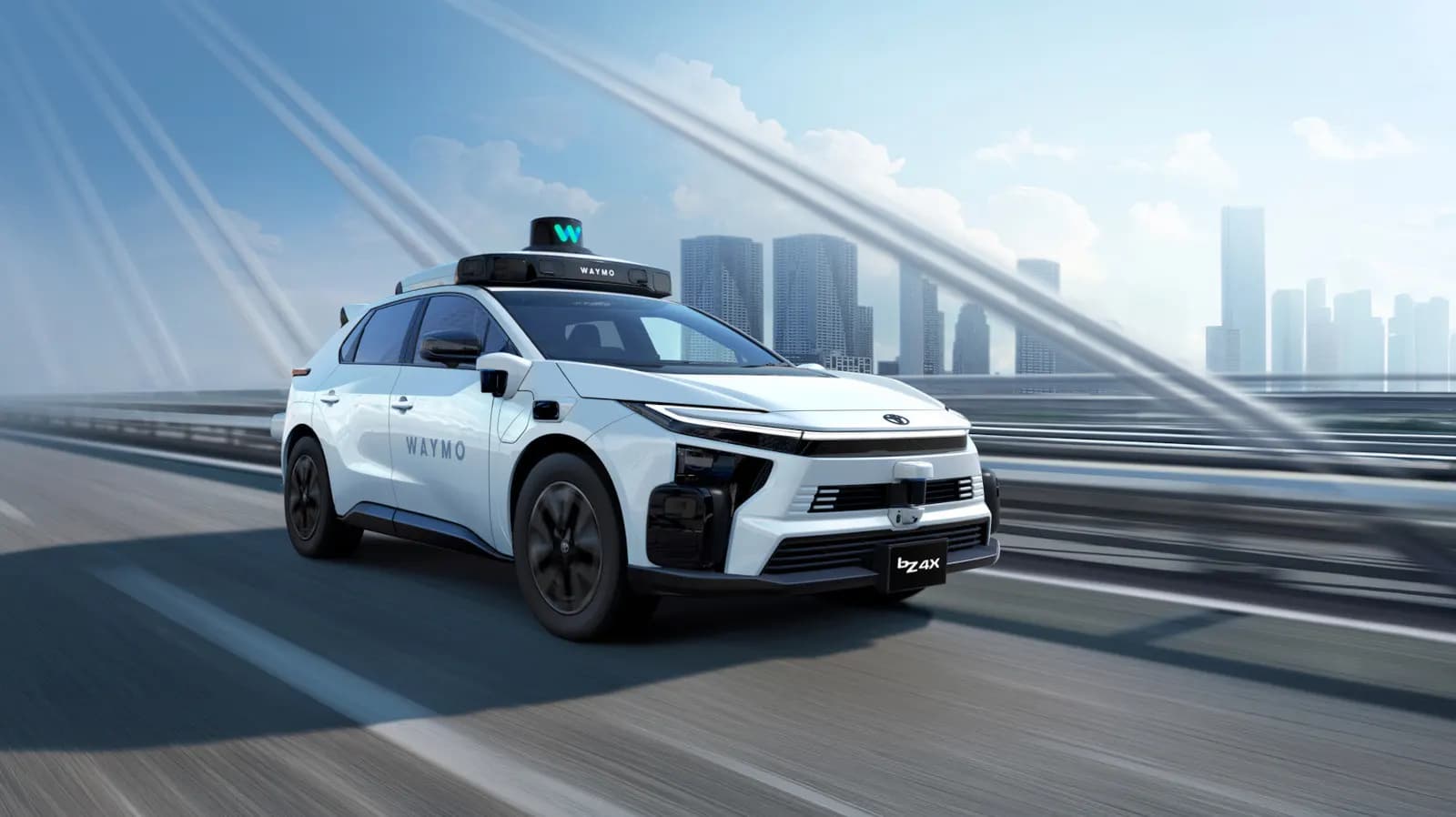 Waymo logolu beyaz otonom Toyota bZ4X, arkada gökdelenler bulunan bir yolda hızla ilerliyor.